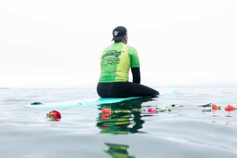 Operation Surf participant sitting on a surfboard in the ocean